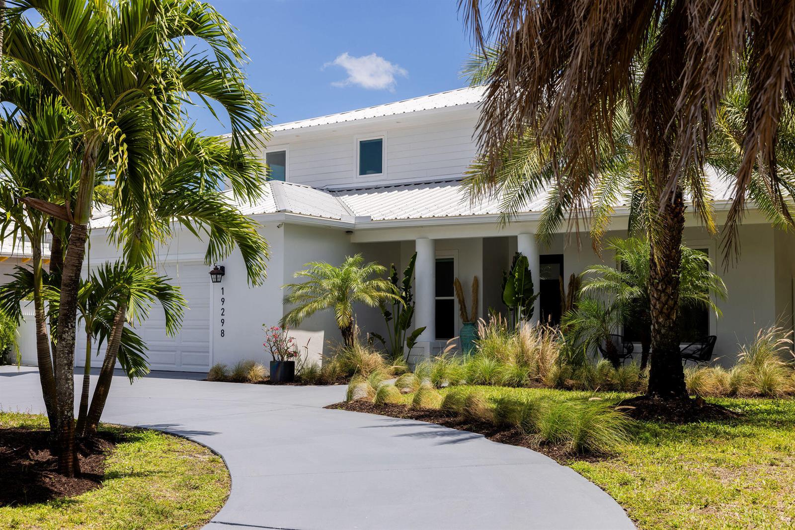 A white two-story house with a metal roof and a curved gray driveway — 19298 Gulfstream Drive, Jupiter FL 33469, JUPITER, FL