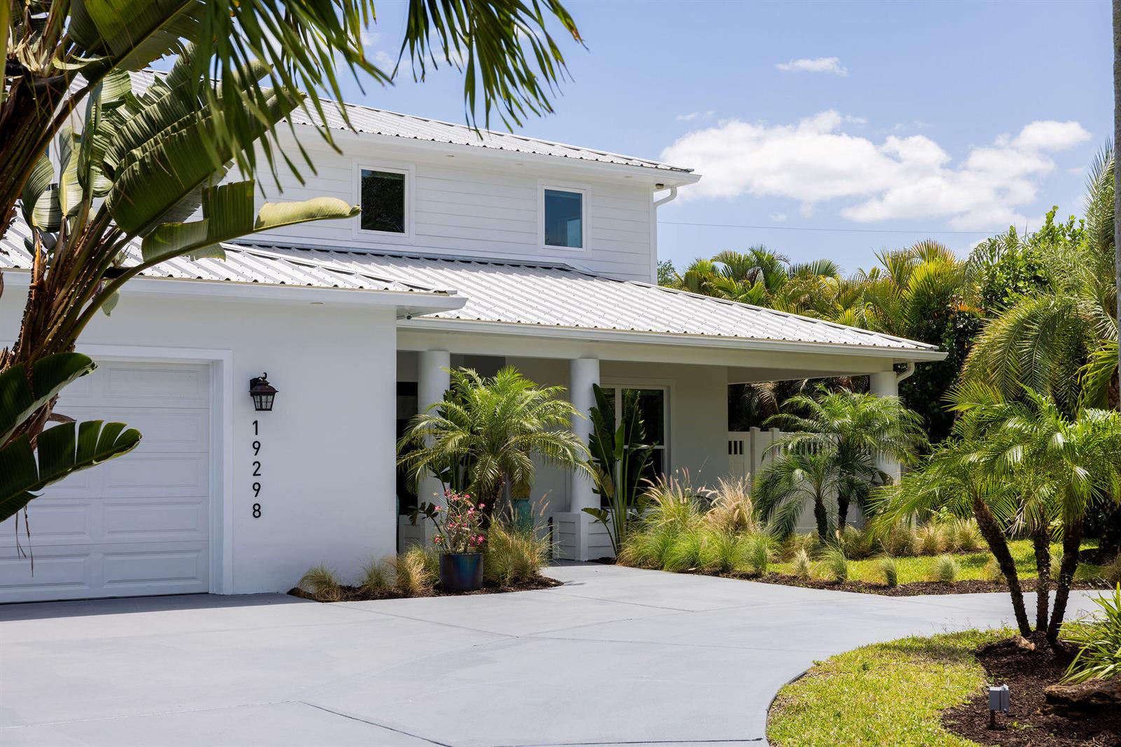 A white two-story house with a metal roof and a paved driveway surrounded by palms — 19298 Gulfstream Drive, Jupiter FL 33469, JUPITER, FL