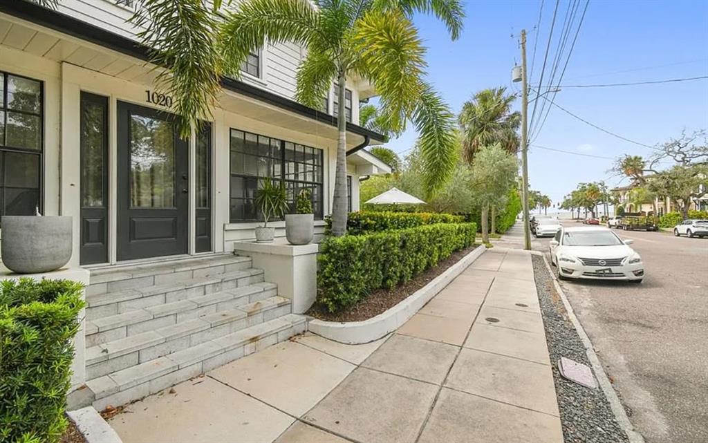 The exterior of a white house features a dark front door, stone steps, and landscaping — 1020 S ROME AVENUE UNIT 2, TAMPA, FL