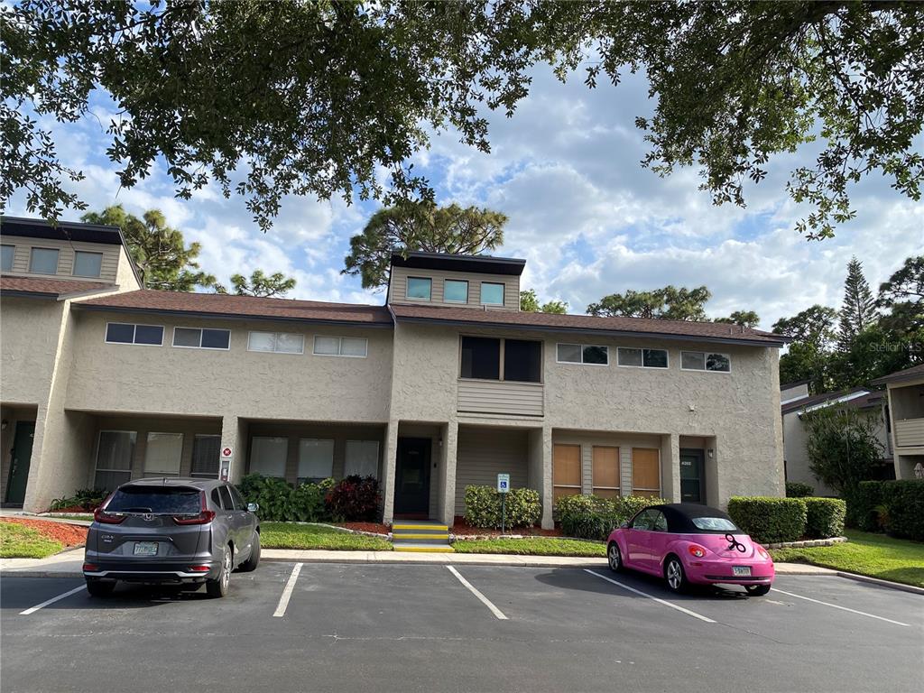 A two-story tan apartment building with a parking lot in front and two parked cars — 4394 SANDNER DRIVE, SARASOTA, FL