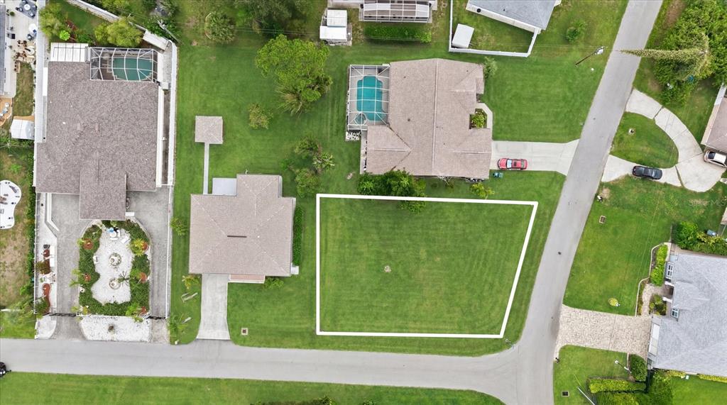 This aerial view shows a vacant residential lot outlined in white next to existing houses — 320 SAN RAFAEL AVENUE, NORTH PORT, FL