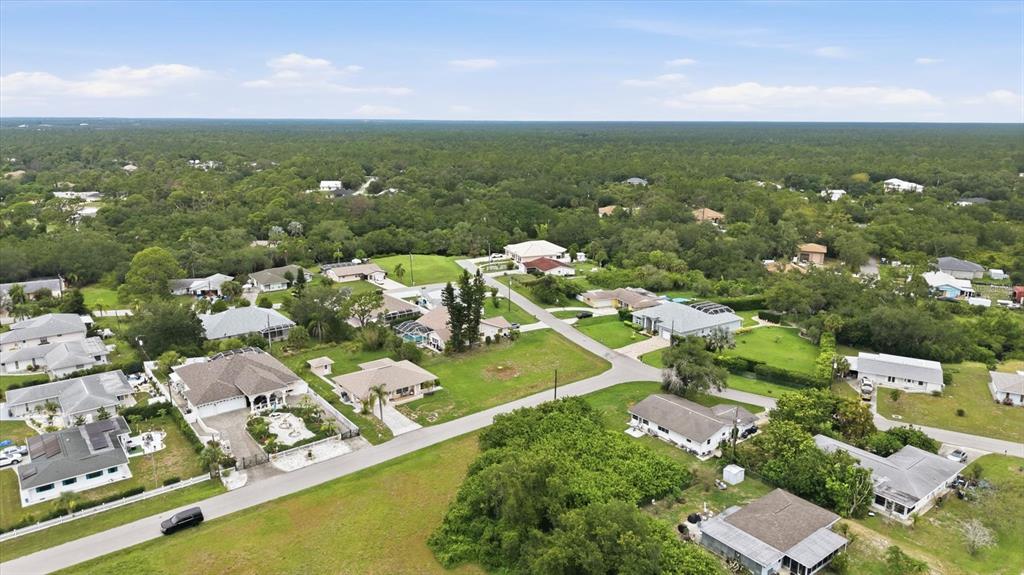 An aerial view shows a suburban neighborhood with single-family homes surrounded by dense green trees — 320 SAN RAFAEL AVENUE, NORTH PORT, FL