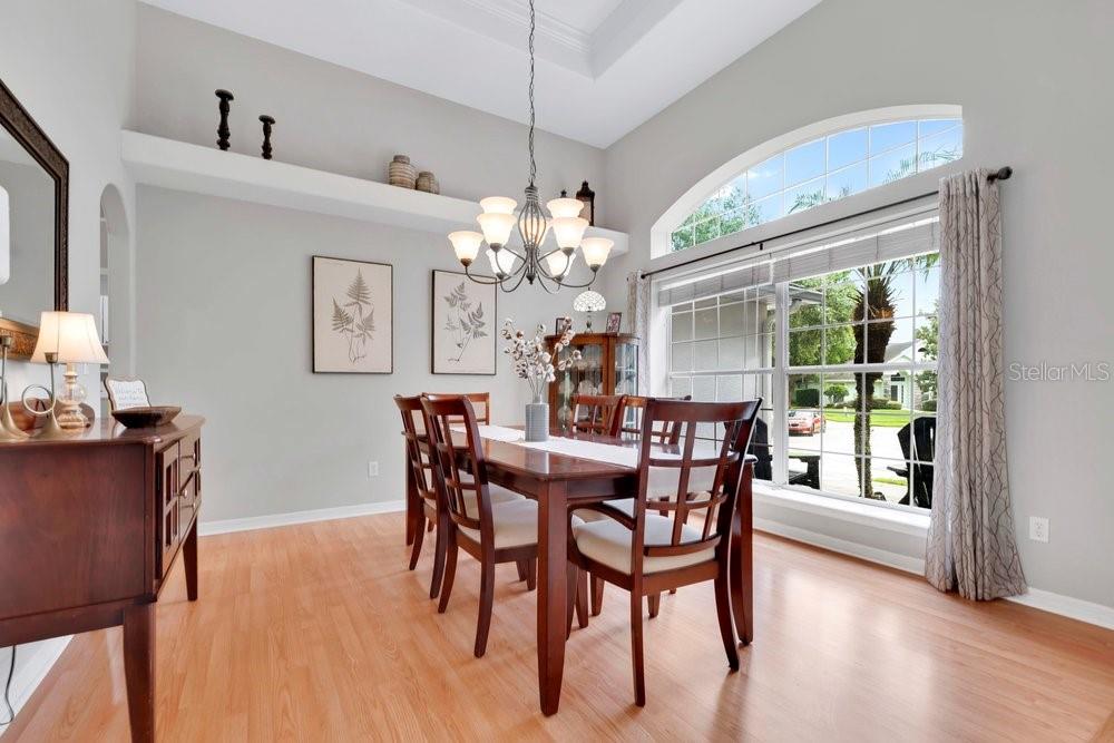 A dining room with hardwood floors, a wooden table, chairs, and a large arched window — 557 QUAIL CREST COURT, DEBARY, FL
