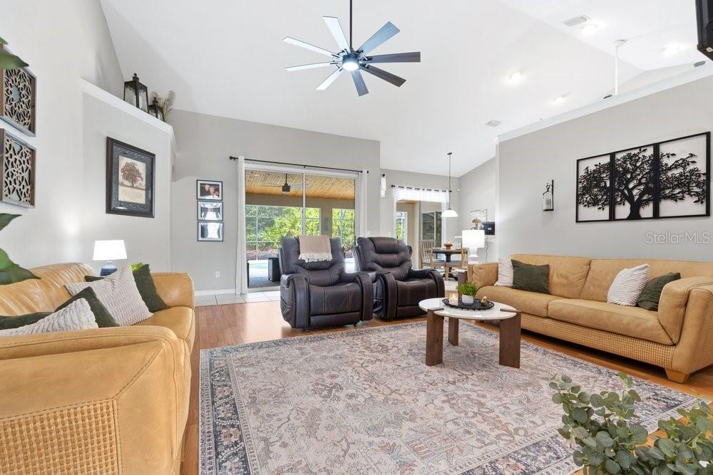 A living room with two tan sofas, two dark recliners, and a large patterned area rug — 557 QUAIL CREST COURT, DEBARY, FL
