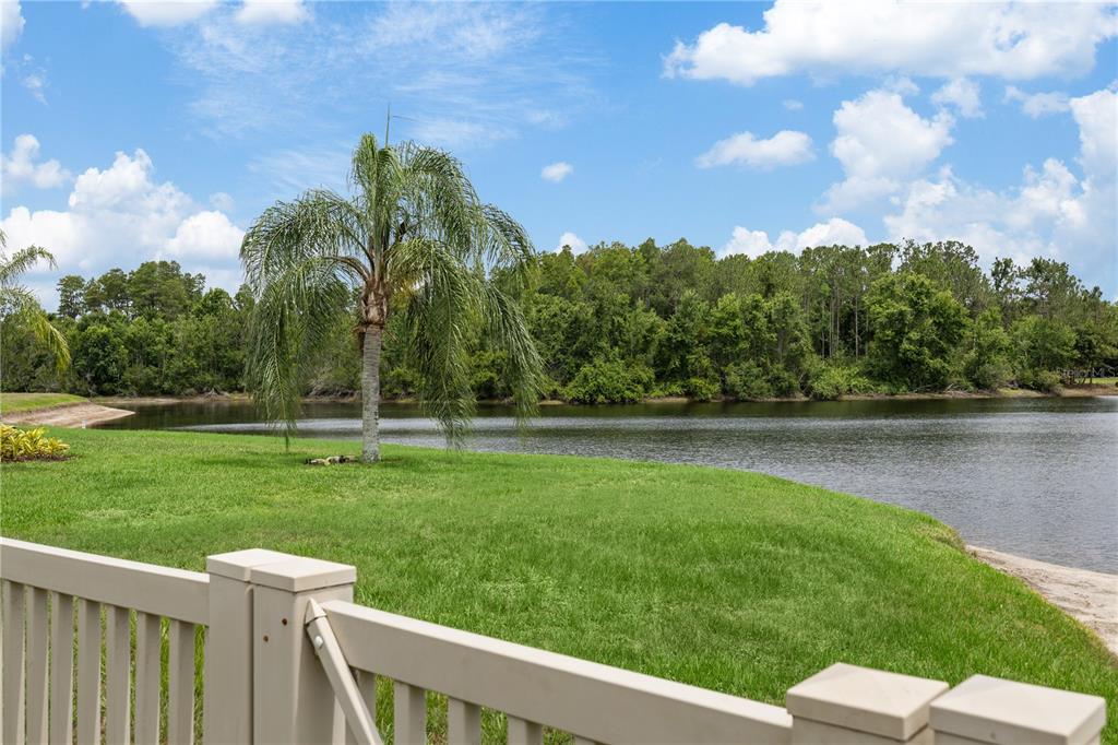 A view of a grassy lawn and a pond from behind a wooden deck railing — 3015 LYNWOOD COURT, LAND O LAKES, FL