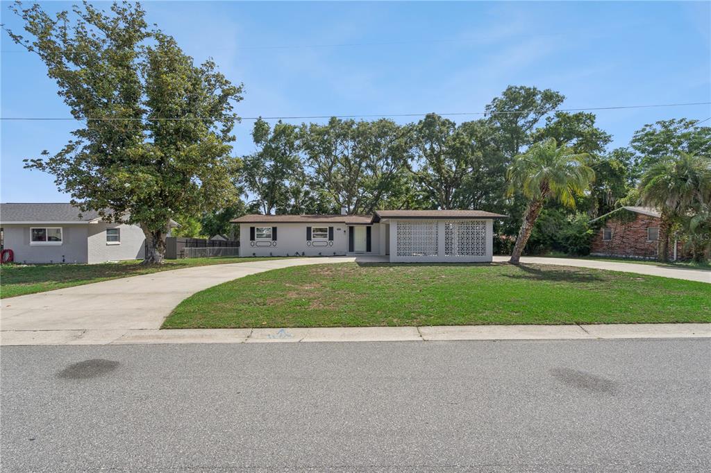 A single-story house with a concrete driveway and a decorative breeze block porch screen — 1310 LEE COURT, LEESBURG, FL
