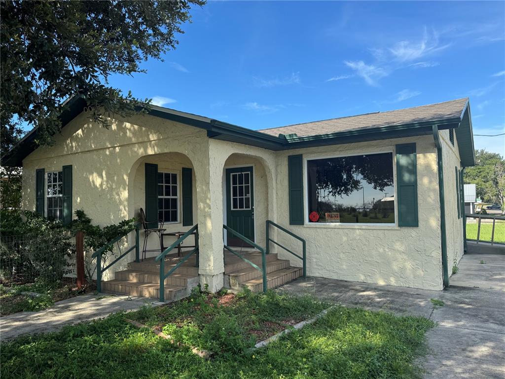 A single-story house with yellow stucco siding, green shutters, and a covered front porch — 225 N SCENIC HIGHWAY, FROSTPROOF, FL