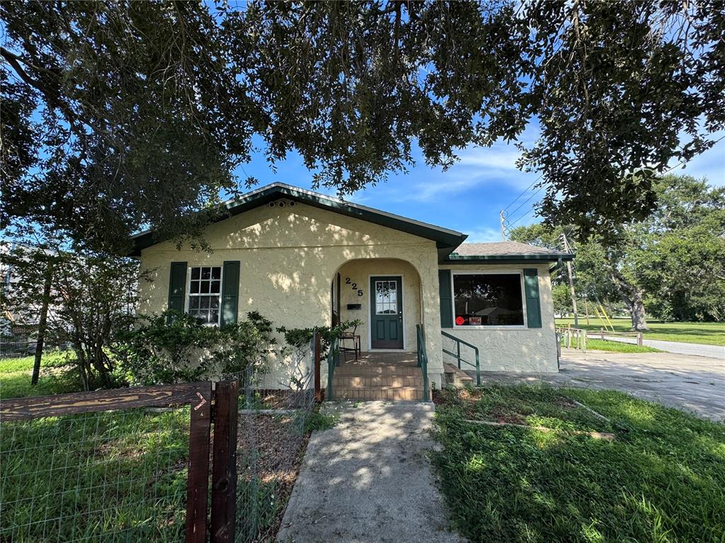 A single-story stucco house with a front porch, green shutters, and a concrete walkway — 225 N SCENIC HIGHWAY, FROSTPROOF, FL