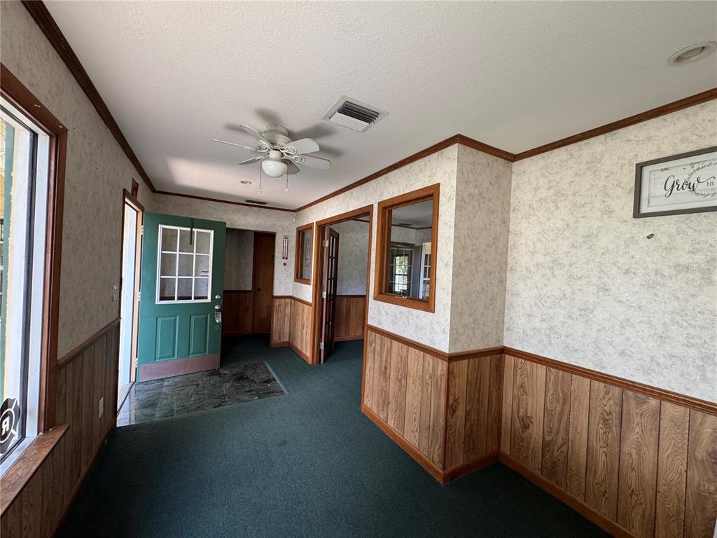 An interior view of a room with green carpeting, wood paneling, and a green door — 225 N SCENIC HIGHWAY, FROSTPROOF, FL
