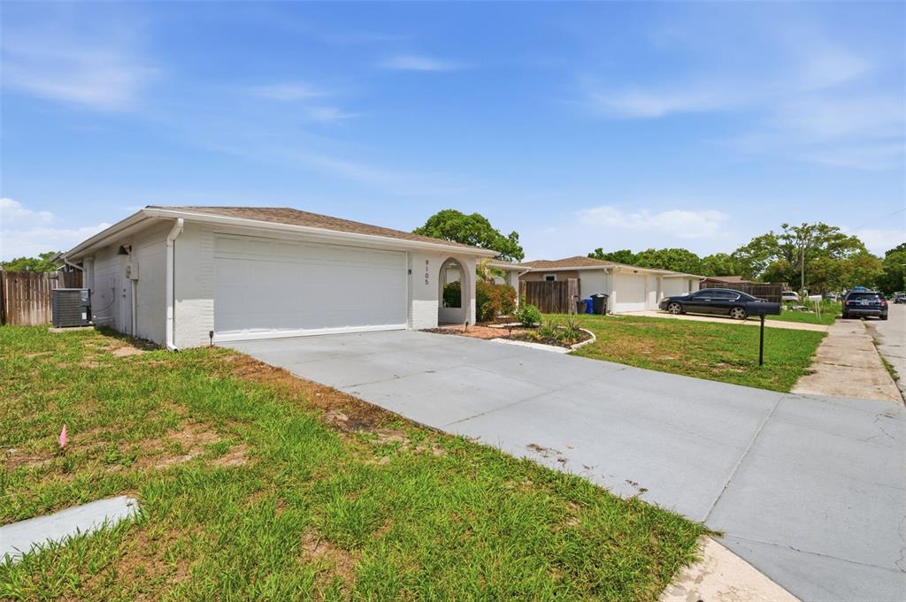 A single-story white house with a two-car garage and a concrete driveway — 9105 HUNT CLUB LANE, PORT RICHEY, FL
