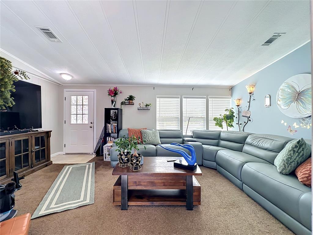 A living room features a large blue sectional sofa, a wooden coffee table, and a television — 7519 CHARLIN PARKWAY, ORLANDO, FL