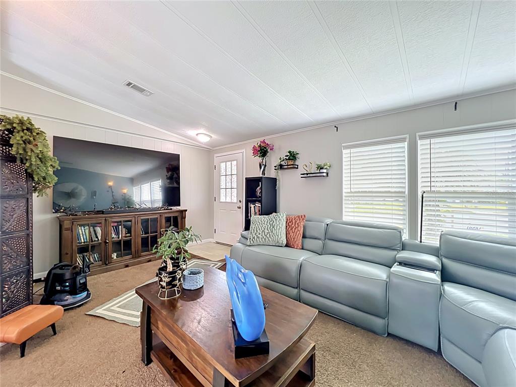 A living room features a large television, a blue leather sectional, and a wooden coffee table — 7519 CHARLIN PARKWAY, ORLANDO, FL