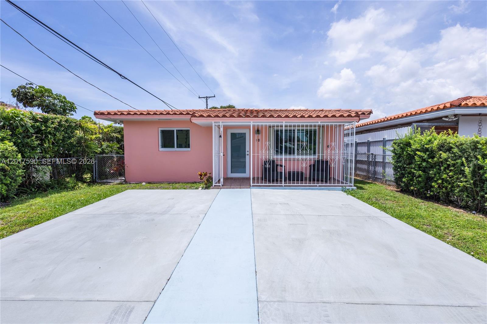 A single-story pink house features a tiled roof, a front porch, and a concrete driveway — 10 NW 60th Ct, Miami FL 33126, MIAMI, FL
