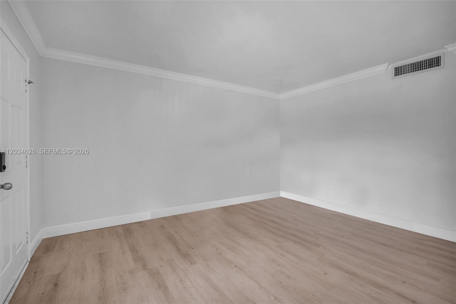 An empty room features light gray walls, white crown molding, and light wood-look flooring — 3245 Virginia St # 48, Miami FL 33133, MIAMI, FL