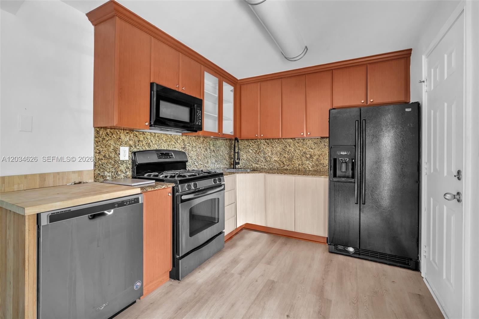 A kitchen features wood cabinets, granite countertops, stainless steel appliances, and a black refrigerator — 3245 Virginia St # 48, Miami FL 33133, MIAMI, FL