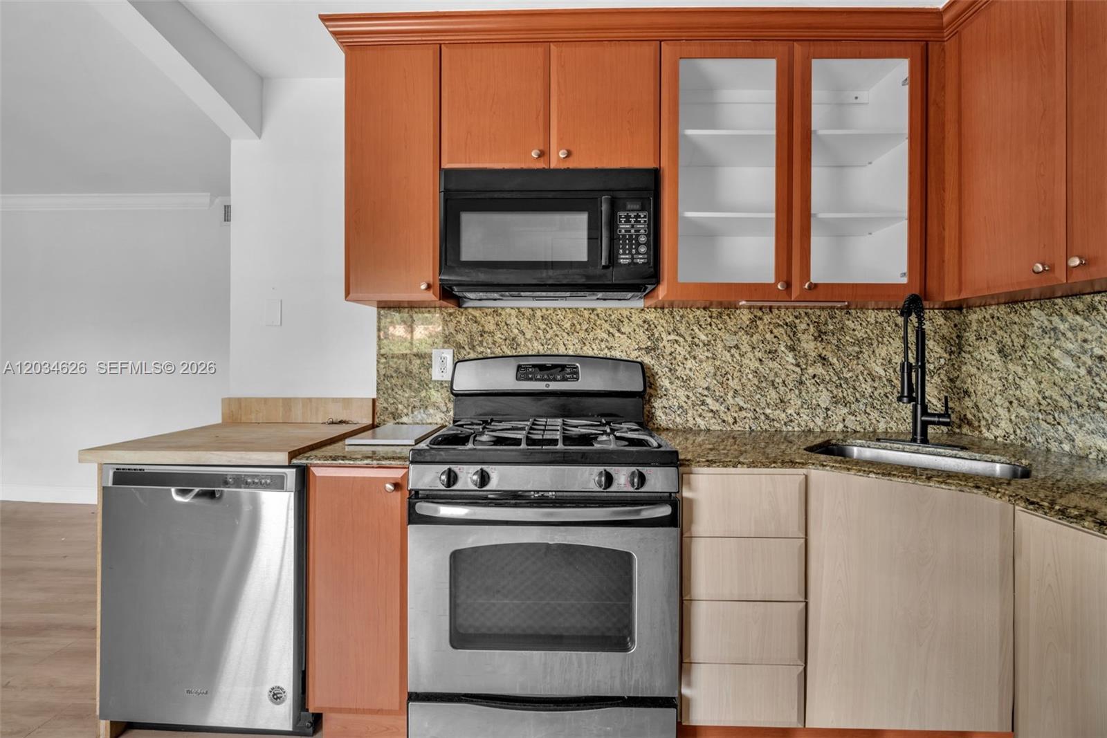 A kitchen features wood cabinets, stainless steel appliances, and a granite countertop with a sink — 3245 Virginia St # 48, Miami FL 33133, MIAMI, FL