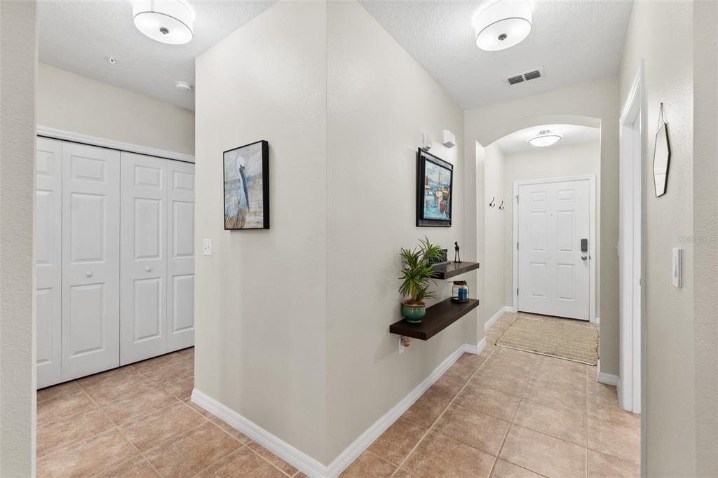 A tiled entryway features a white front door, floating shelves, and a double-door closet — 100 CANOPY WALK LANE UNIT 124, PALM COAST, FL