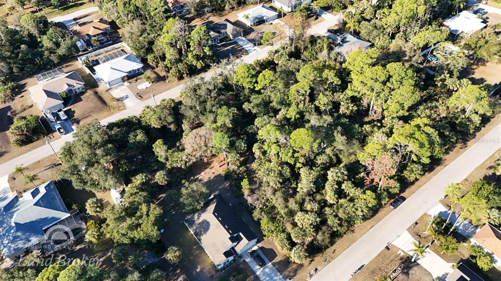 An aerial view shows a wooded lot situated between two residential streets and houses — SPARKLE LANE, NORTH PORT, FL