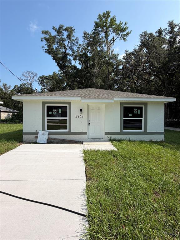 A single-story house with a white exterior, a front door, and two windows — 2163 NW 65TH PLACE, OCALA, FL