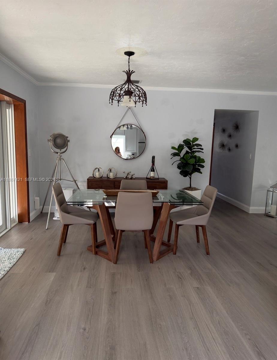 A dining room features a glass-topped table, four chairs, a sideboard, and a round mirror — 9021 SW 197th St, Cutler Bay FL 33157, CUTLER BAY, FL