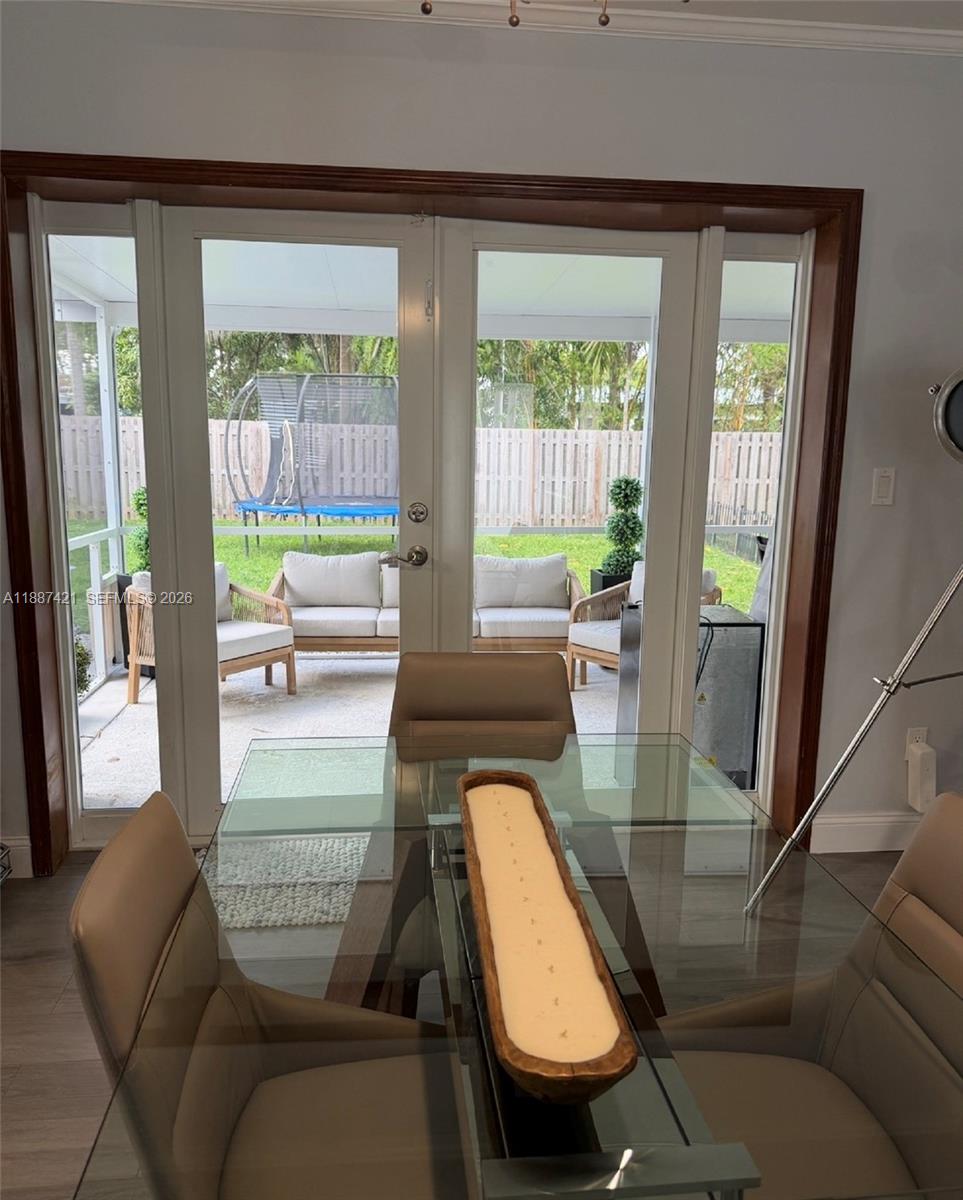 A dining room with a glass table overlooks a screened-in patio and backyard — 9021 SW 197th St, Cutler Bay FL 33157, CUTLER BAY, FL