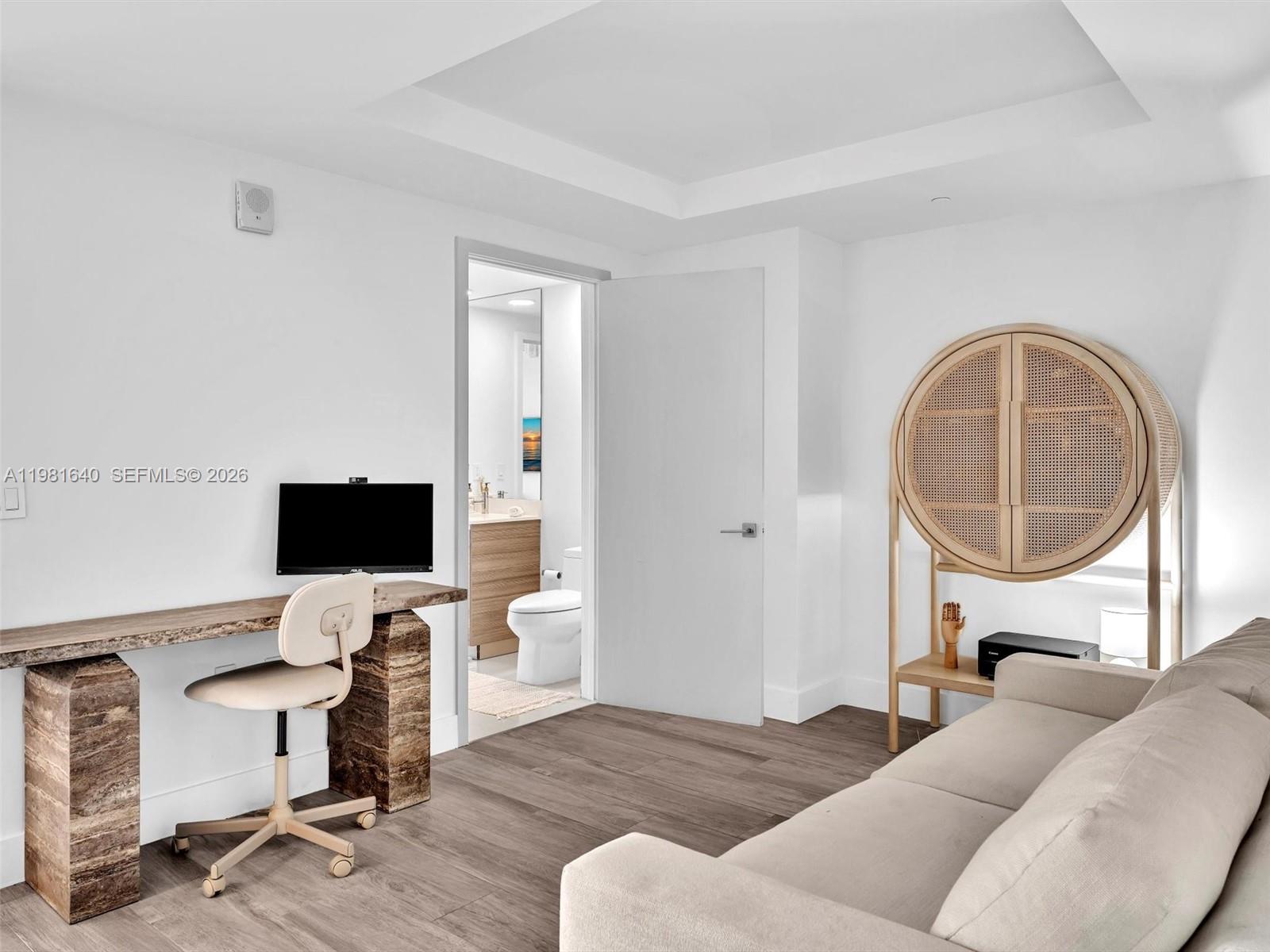 A room features a desk, a sofa, a circular cabinet, and a doorway to a bathroom — 121 NE 34th St # 2102, Miami FL 33137, MIAMI, FL