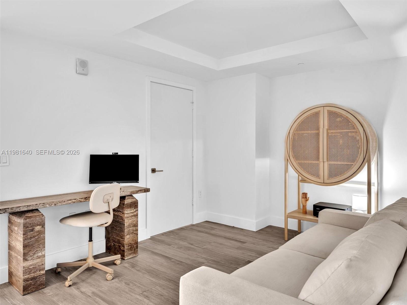 A home office features a stone-base desk, a beige chair, and a circular rattan cabinet — 121 NE 34th St # 2102, Miami FL 33137, MIAMI, FL