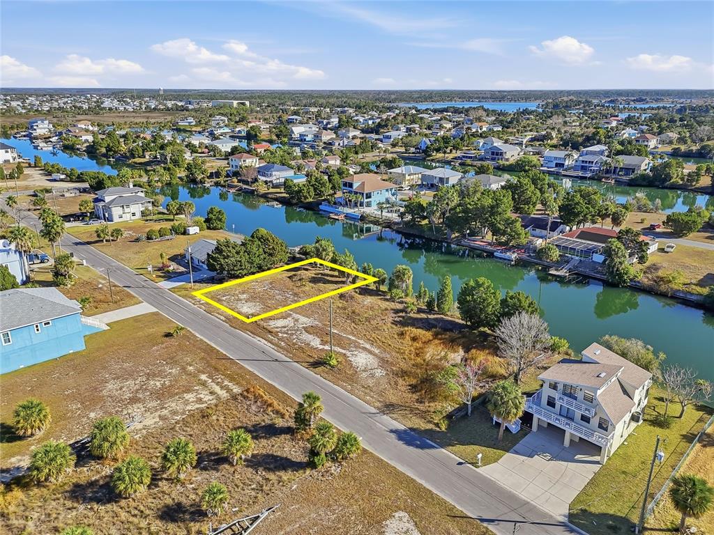 An aerial view shows a vacant, rectangular waterfront lot outlined in yellow along a canal — 3318 GARDENIA DRIVE, HERNANDO BEACH, FL