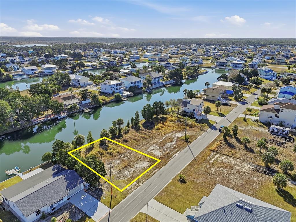 An aerial view shows a vacant waterfront lot outlined in yellow next to a road — 3318 GARDENIA DRIVE, HERNANDO BEACH, FL