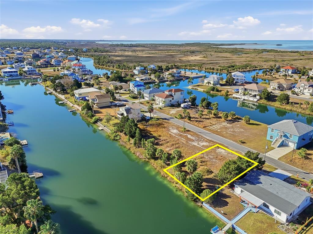 An aerial view shows a vacant waterfront lot outlined in yellow along a canal — 3318 GARDENIA DRIVE, HERNANDO BEACH, FL