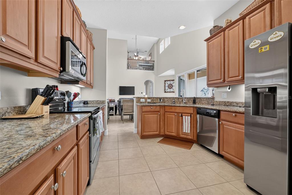 A kitchen with wood cabinets, granite countertops, stainless steel appliances, and tile flooring — 3421 TORRE BOULEVARD, NEW SMYRNA BEACH, FL
