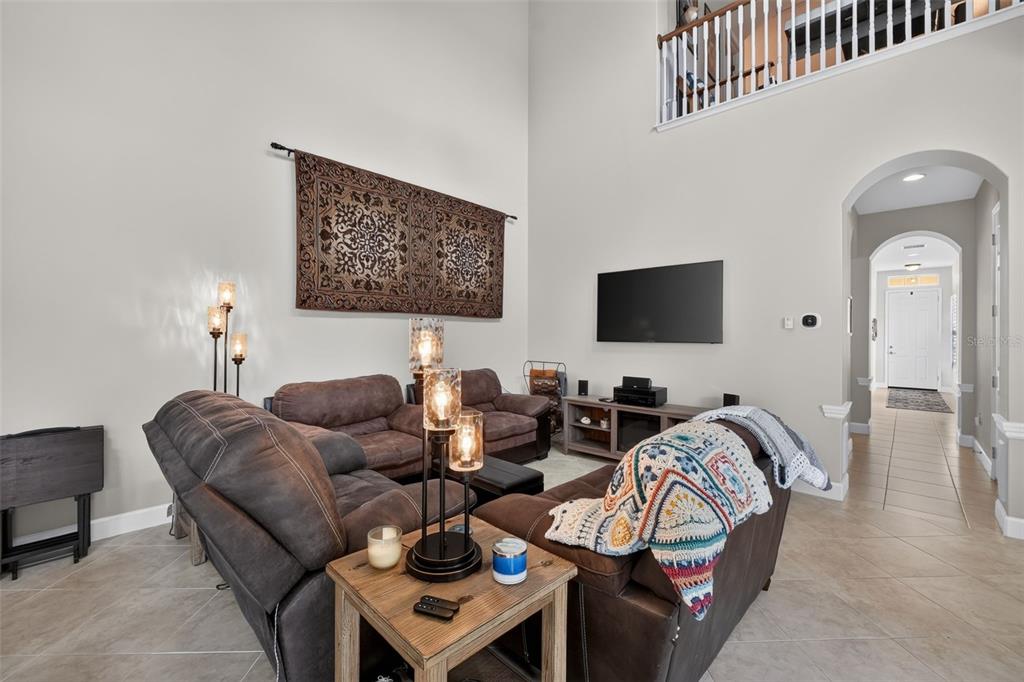A living room features high ceilings, brown furniture, a wall tapestry, and tile flooring — 3421 TORRE BOULEVARD, NEW SMYRNA BEACH, FL