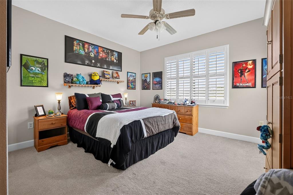 A bedroom with a bed, wooden furniture, Pixar-themed wall art, and a ceiling fan — 3421 TORRE BOULEVARD, NEW SMYRNA BEACH, FL
