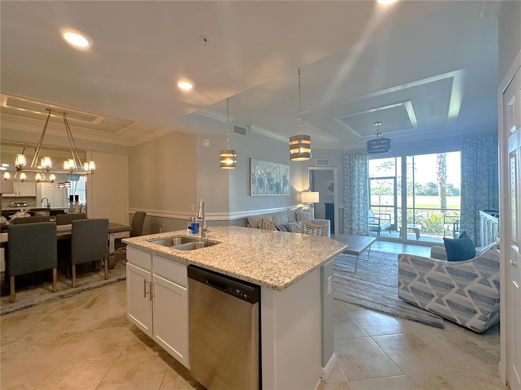 A kitchen island with granite countertops overlooks an open-concept living and dining area — 14061 HERITAGE LANDING BOULEVARD UNIT 418, PUNTA GORDA, FL