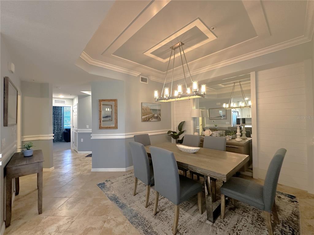 A dining room features a rectangular table, six gray chairs, and a modern chandelier — 14061 HERITAGE LANDING BOULEVARD UNIT 418, PUNTA GORDA, FL