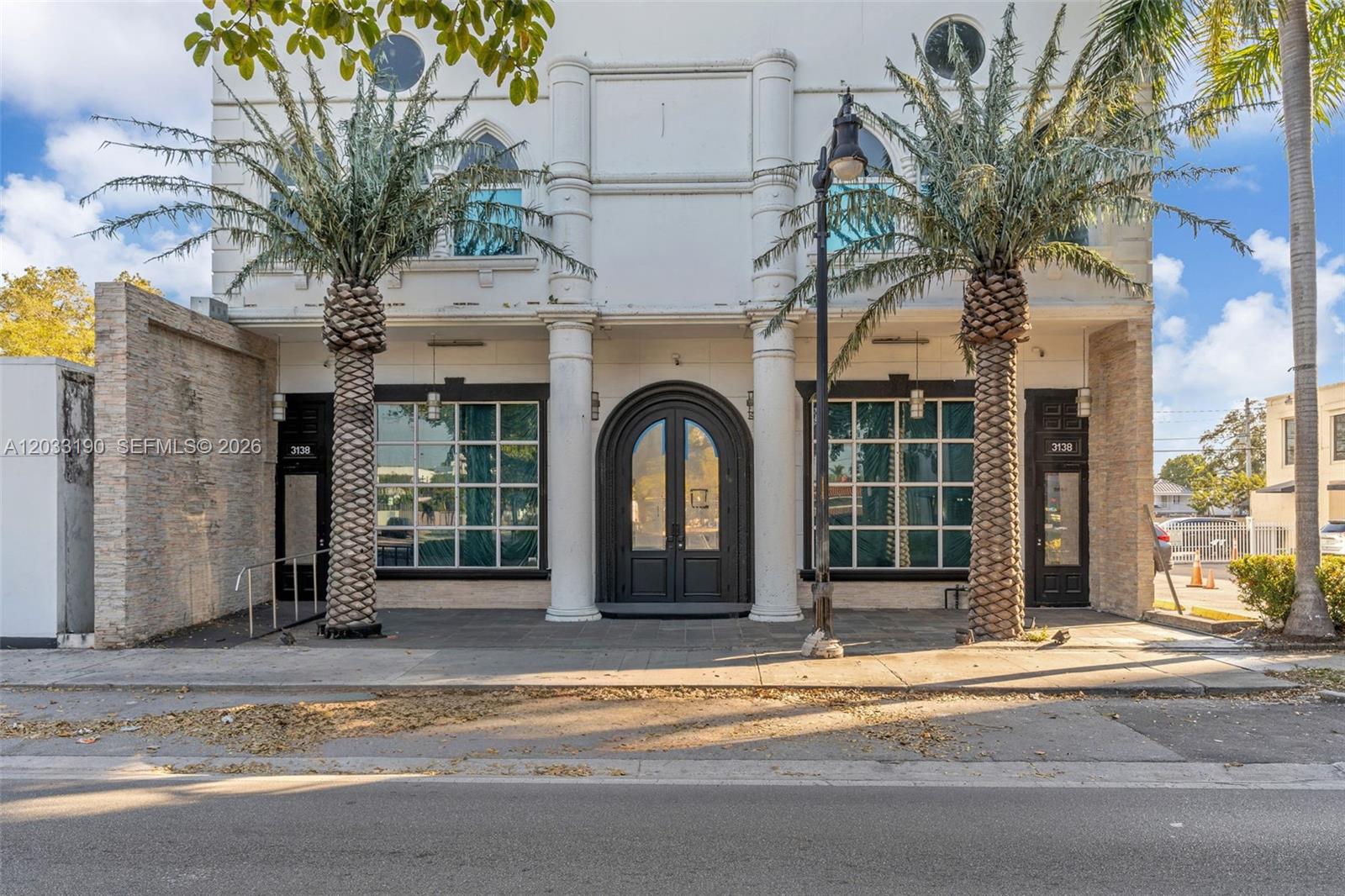 The exterior of a two-story white building features a central arched doorway and two palm trees — 3138 Coral Way, Miami FL 33145, MIAMI, FL