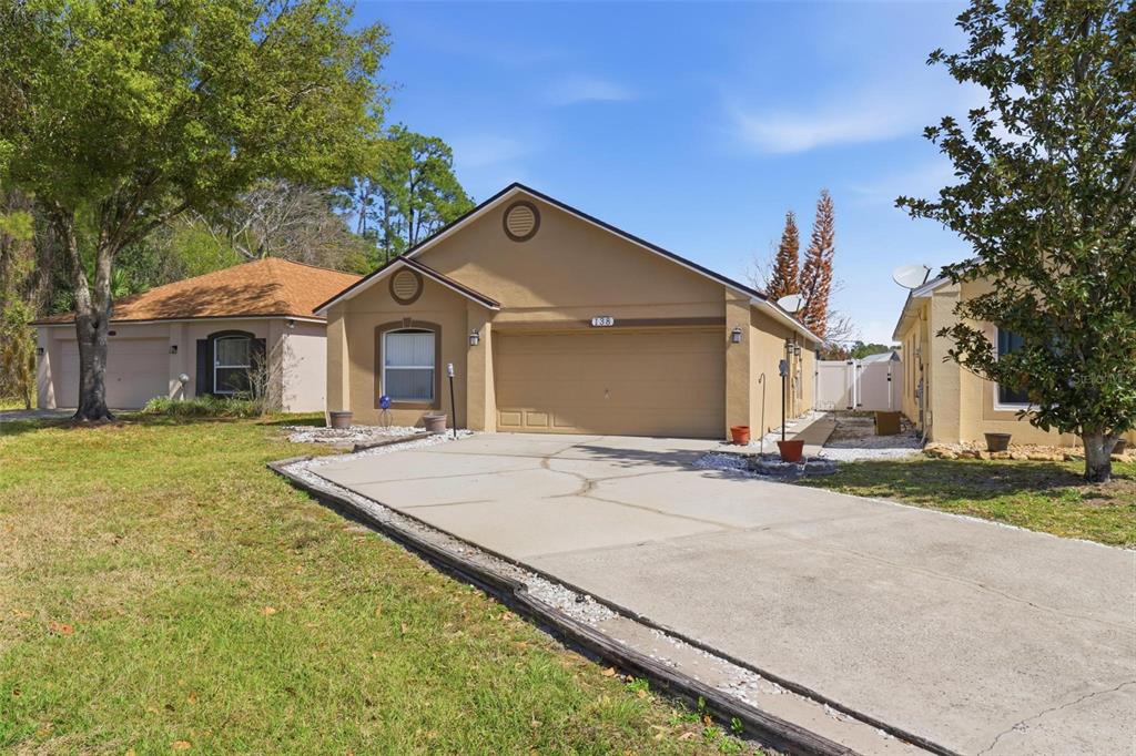 A tan, single-story house with a two-car garage and a concrete driveway — 138 PLACID WOODS COURT, SANFORD, FL