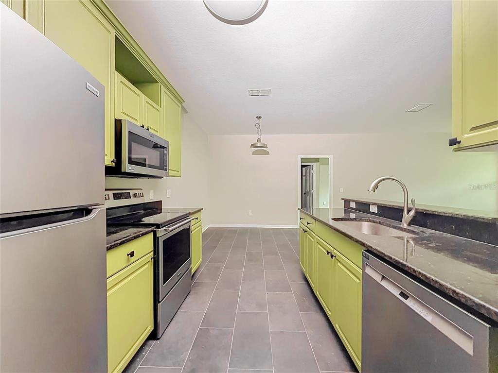 A kitchen with lime green cabinets, stainless steel appliances, dark countertops, and gray tile flooring — 6003 HEMINGWAY CIRCLE UNIT 6003, HAINES CITY, FL
