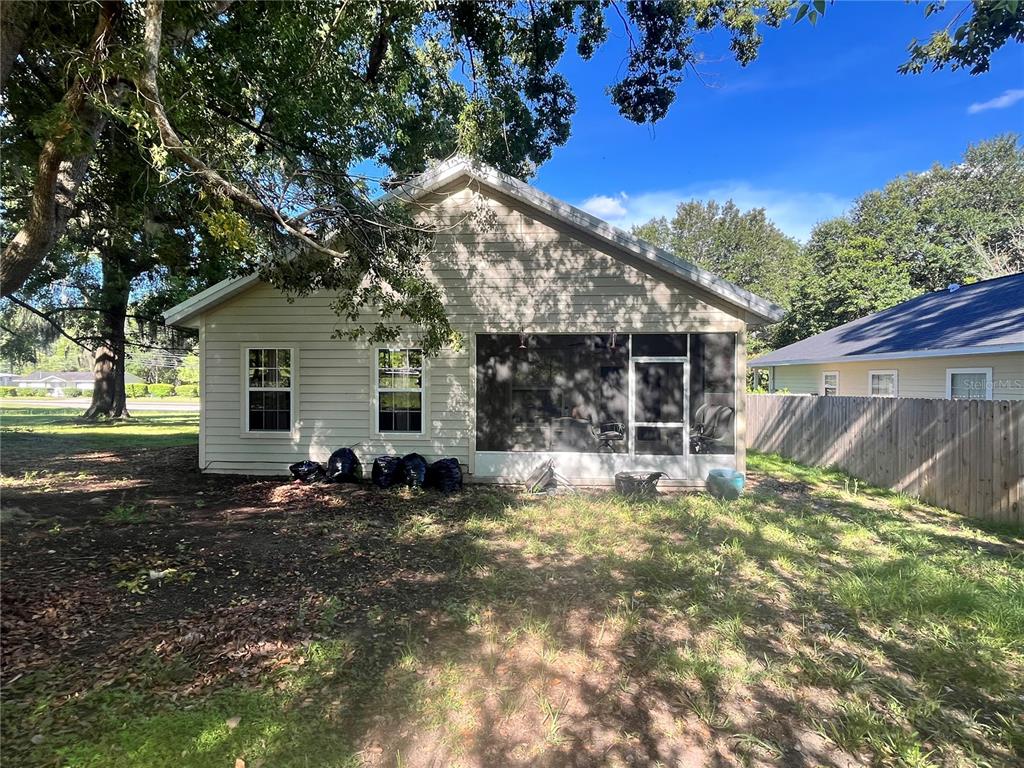 The rear exterior of a house features light-colored siding, two windows, and a screened-in porch — 15704 NW 140TH STREET, ALACHUA, FL