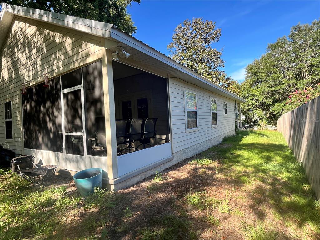 A side view of a house featuring a screened-in porch and light-colored vinyl siding — 15704 NW 140TH STREET, ALACHUA, FL