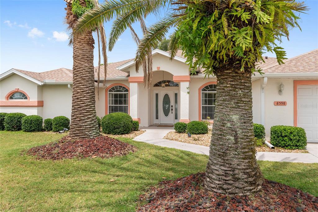 A single-story house with a white stucco exterior, arched windows, and two prominent palm trees — 8598 SW 56TH AVENUE ROAD, OCALA, FL
