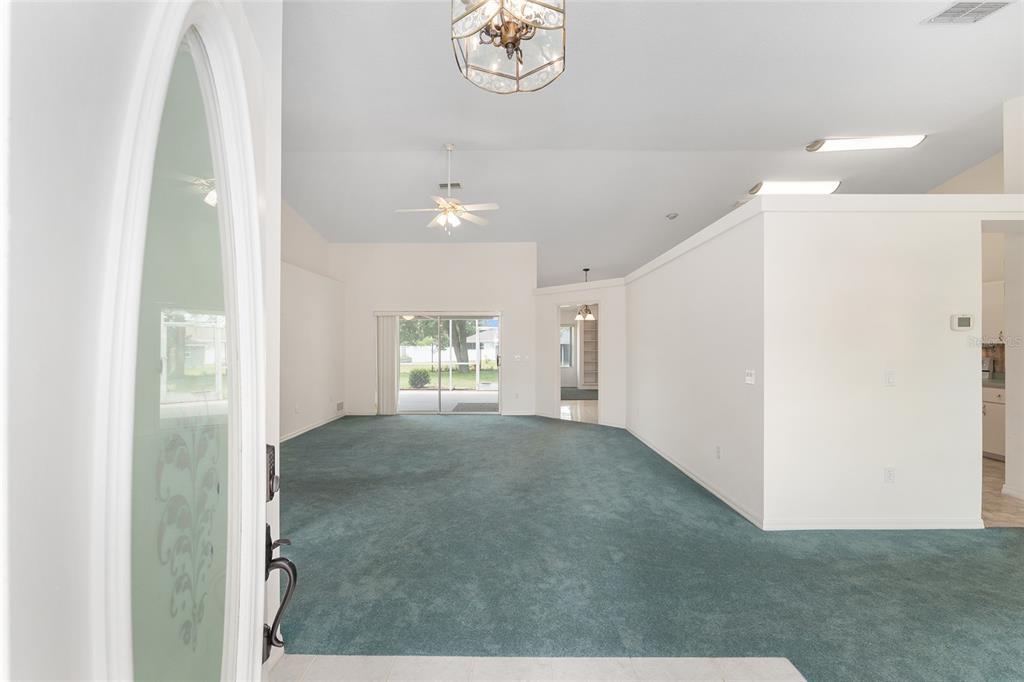 A view from a doorway into a living room with teal carpeting and vaulted ceilings — 8598 SW 56TH AVENUE ROAD, OCALA, FL