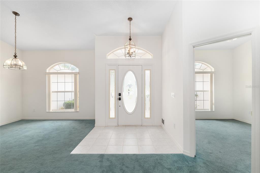 An entryway with a tiled floor, white front door, and teal carpeting in adjacent rooms — 8598 SW 56TH AVENUE ROAD, OCALA, FL