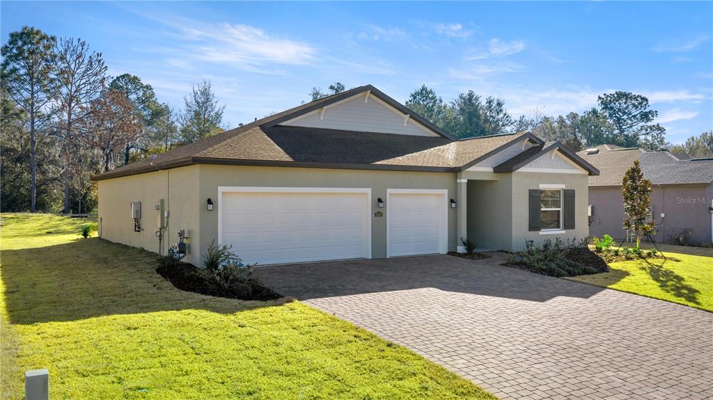 A single-story house with a two-car garage and a paved driveway under a blue sky — 6680 SW 180TH CIRCLE, DUNNELLON, FL