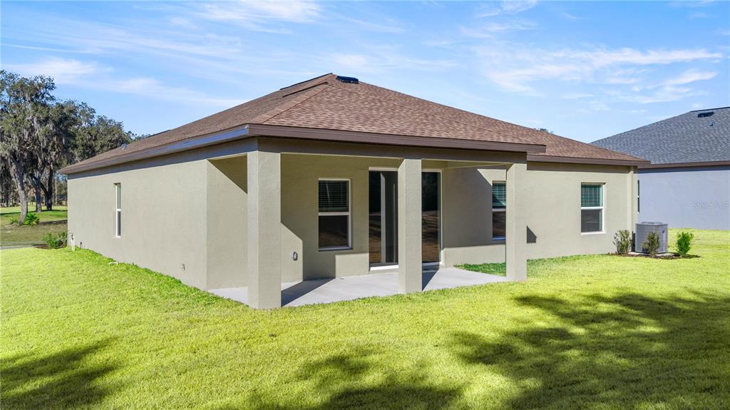 The exterior rear view of a single-story house features a covered concrete patio — 6680 SW 180TH CIRCLE, DUNNELLON, FL