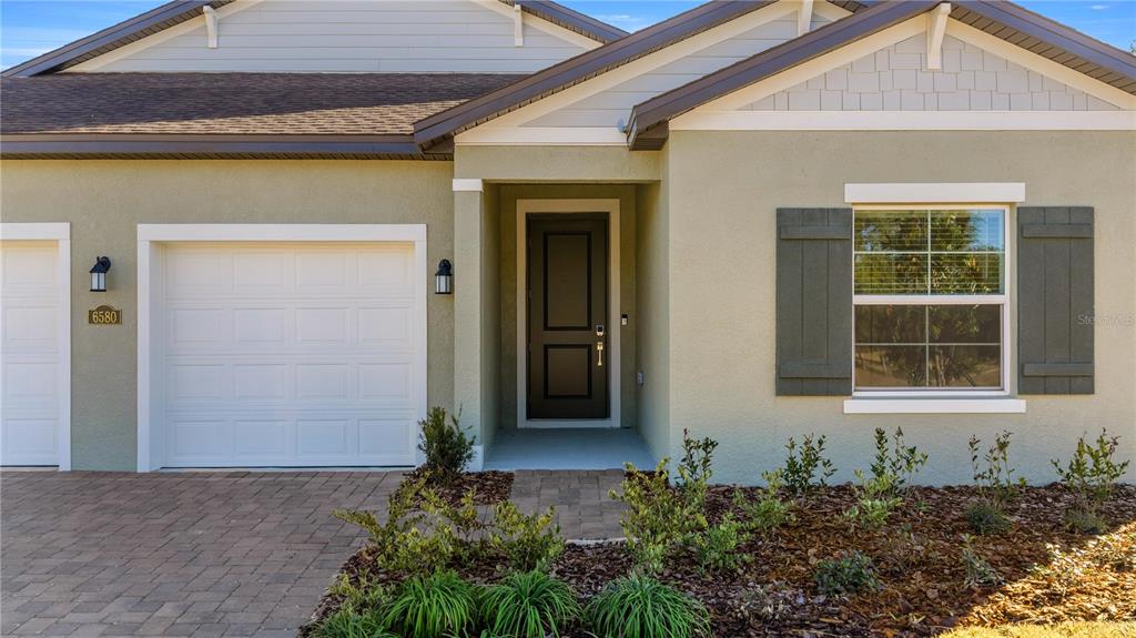 The exterior of a house features a garage, a front door, and a shuttered window — 6680 SW 180TH CIRCLE, DUNNELLON, FL