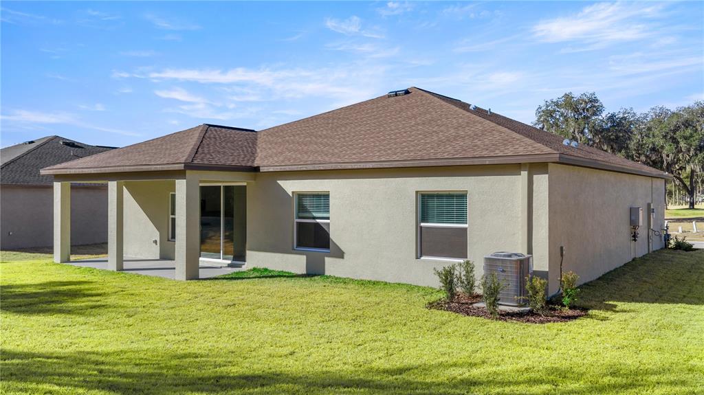 The exterior rear view of a single-story house features a covered patio and lawn — 6680 SW 180TH CIRCLE, DUNNELLON, FL