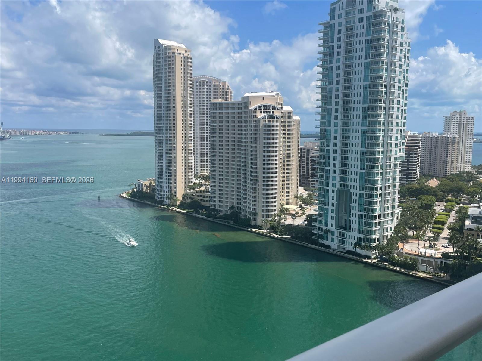 An elevated view of high-rise apartment buildings along a waterfront with a boat nearby — 300 S Biscayne Blvd # 2012, Miami FL 33131, MIAMI, FL
