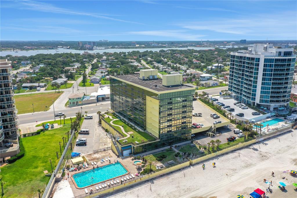 An aerial view shows a multi-story beachfront building with a pool and parking lot — 1909 S ATLANTIC AVENUE UNIT 501, DAYTONA BEACH, FL