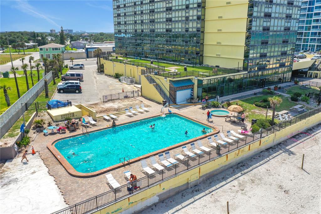 An aerial view shows a rectangular swimming pool and hot tub beside a tall building — 1909 S ATLANTIC AVENUE UNIT 501, DAYTONA BEACH, FL